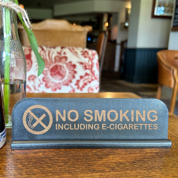 a no smoking sign on a table next to a glass of water